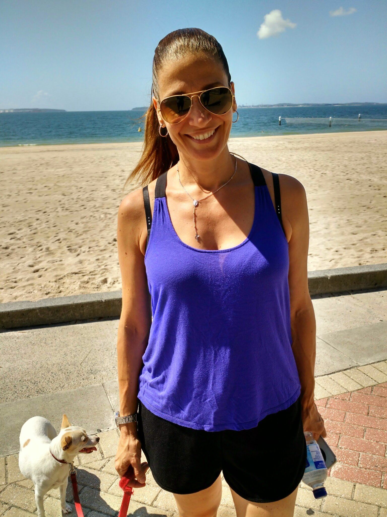Dion, founder of Pawsercise, with a small dog on a Bayside promenade